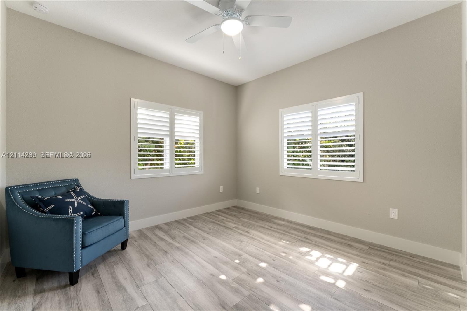 Neutral wall finish, wood-finish flooring, plantation shutters, and a ceiling-mounted light fixture