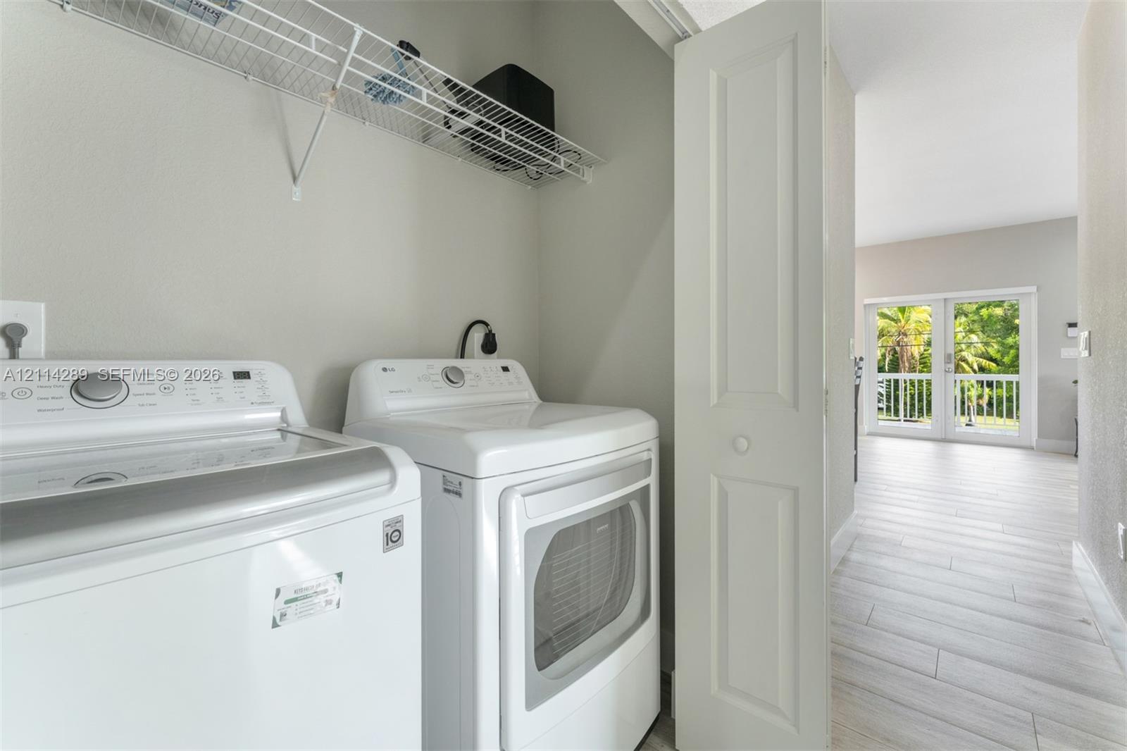 Laundry area featuring built-in wire shelving and light-toned wood-finish flooring