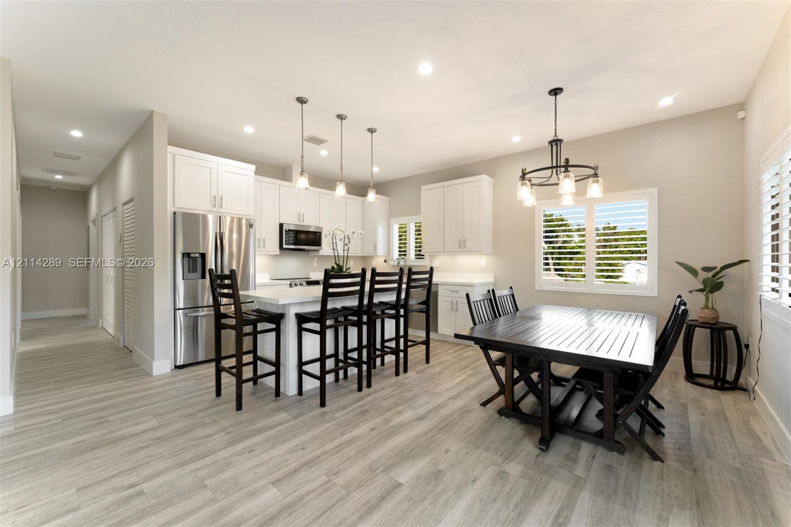 Kitchen featuring white cabinetry, stone countertops, stainless steel appliances, wood-finish flooring, and recessed lighting