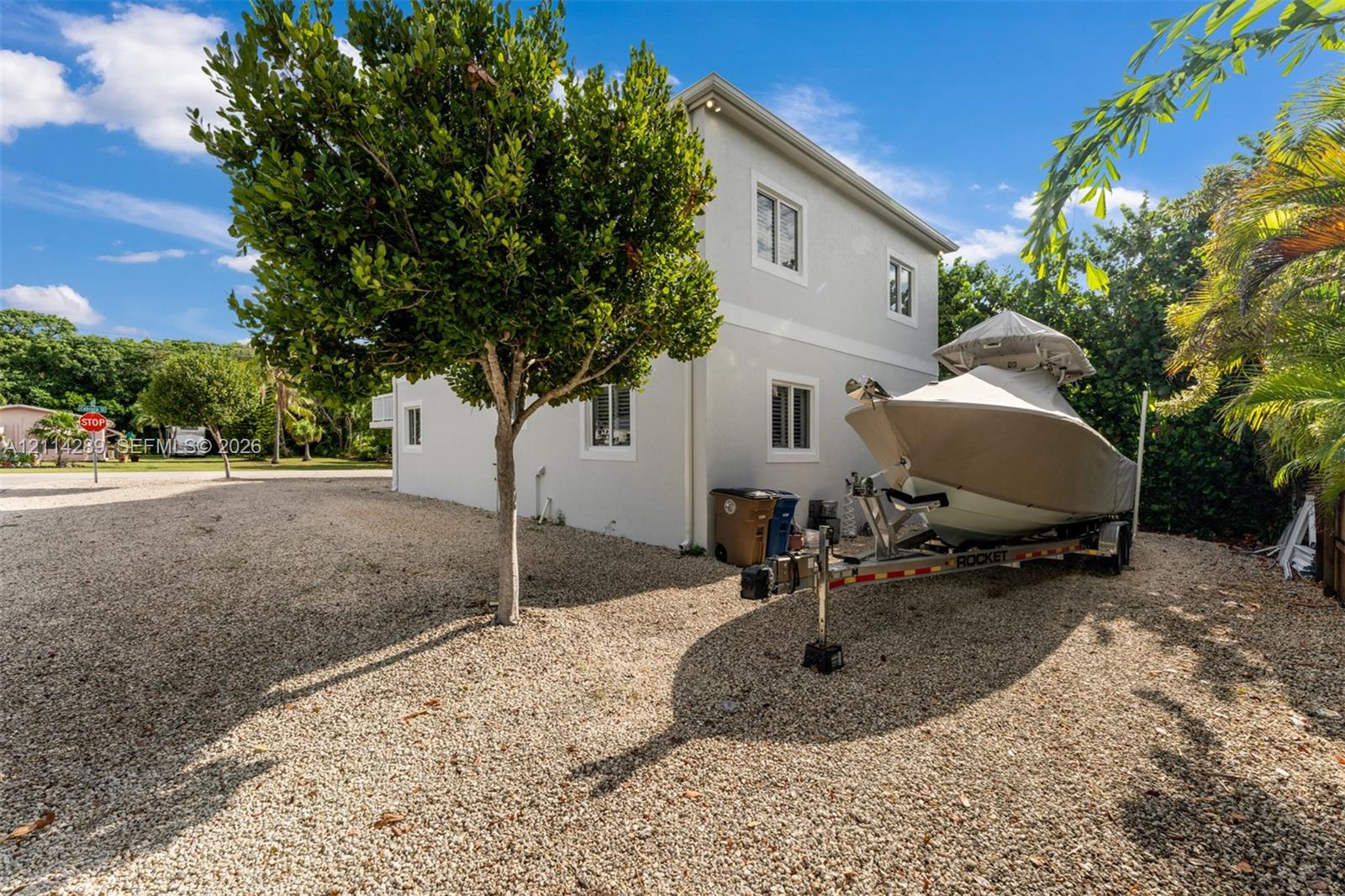 Two-story structure with a light-colored stucco exterior, multi-pane windows, and a gravel lot