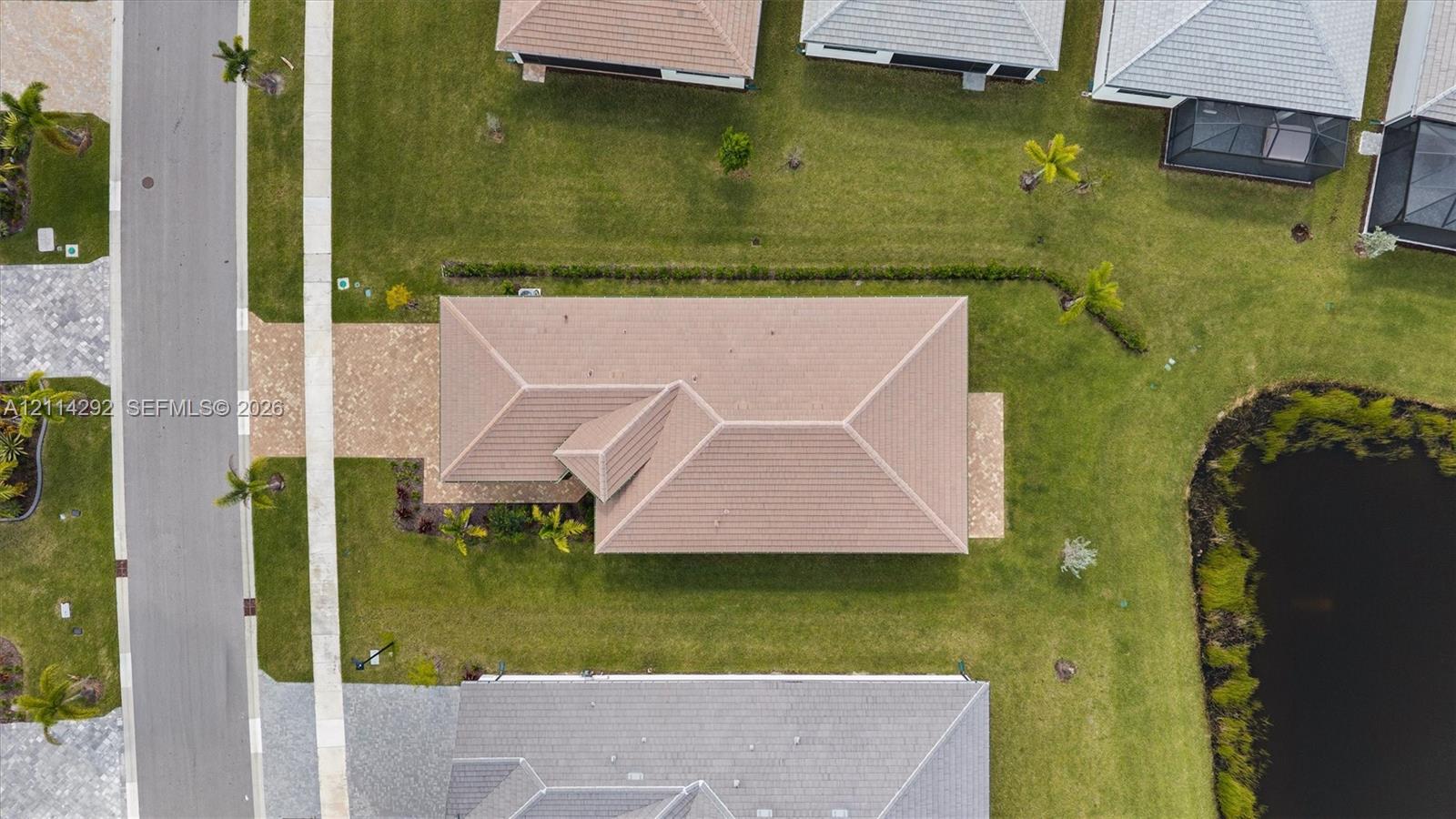Aerial perspective featuring a tile roof, paved driveway, and water frontage