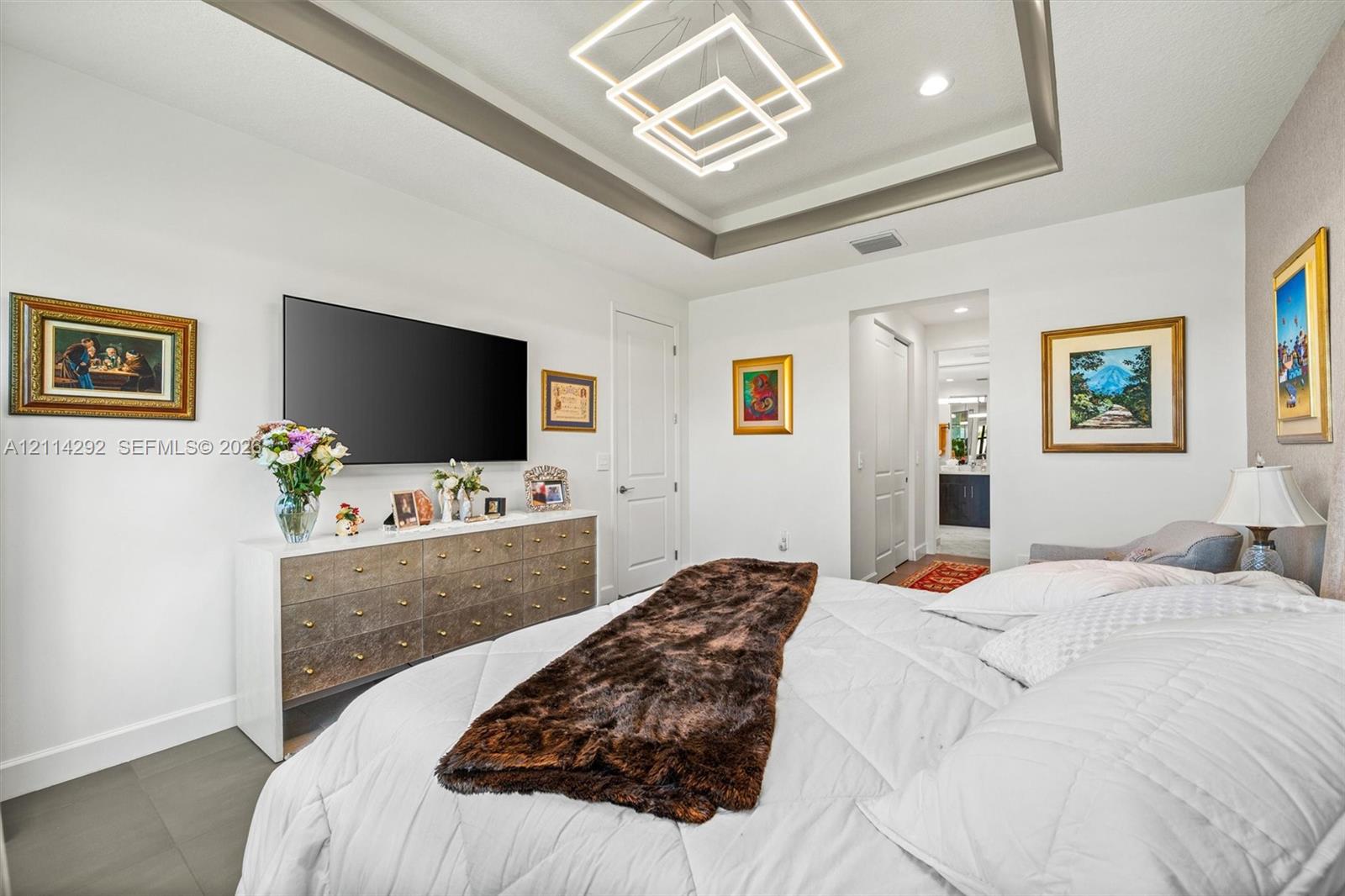 Tray ceiling featuring geometric LED light fixture, recessed lighting, and neutral-toned flooring