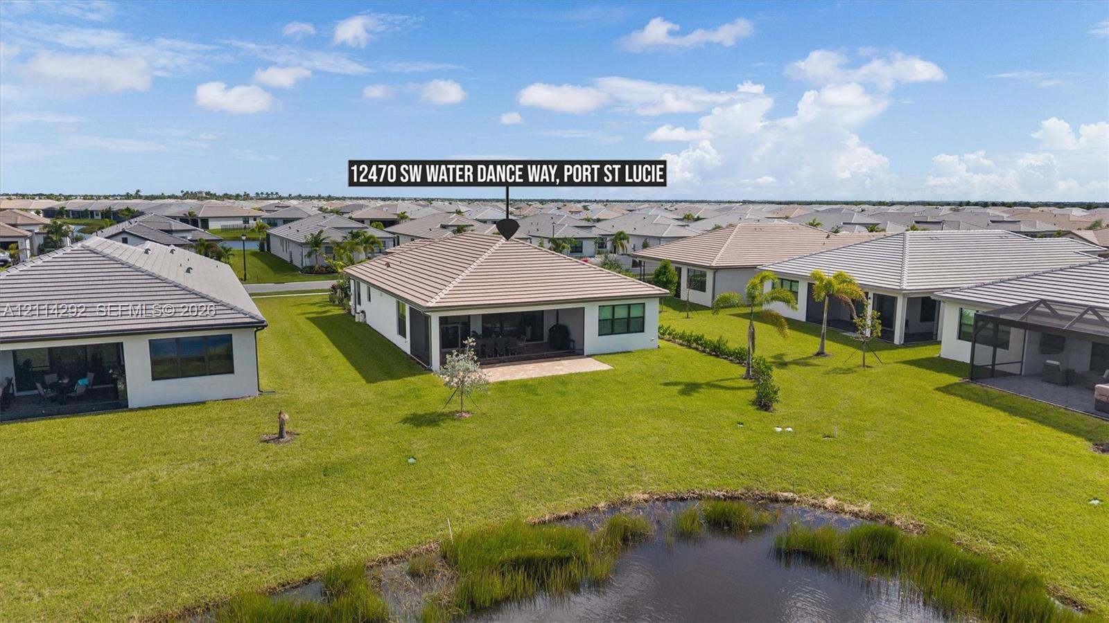 Single-story residence featuring a tile roof, covered rear patio, expansive lawn, and water frontage