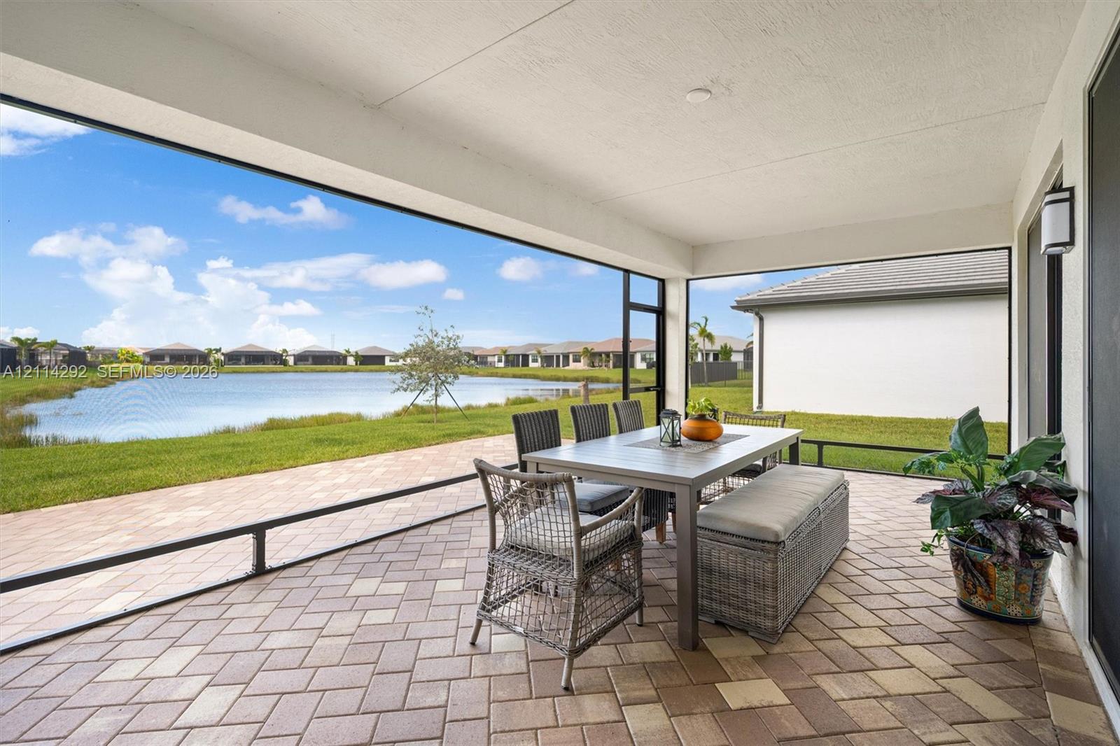 Covered screened-in patio featuring paver flooring and direct water frontage