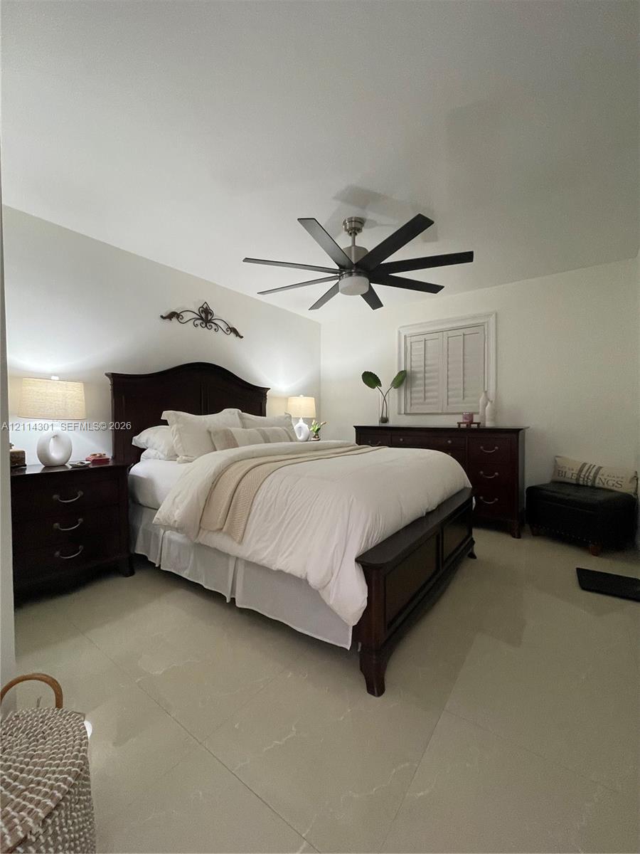 Large-format polished tile flooring, multi-blade ceiling fan with integrated lighting, and plantation shutters