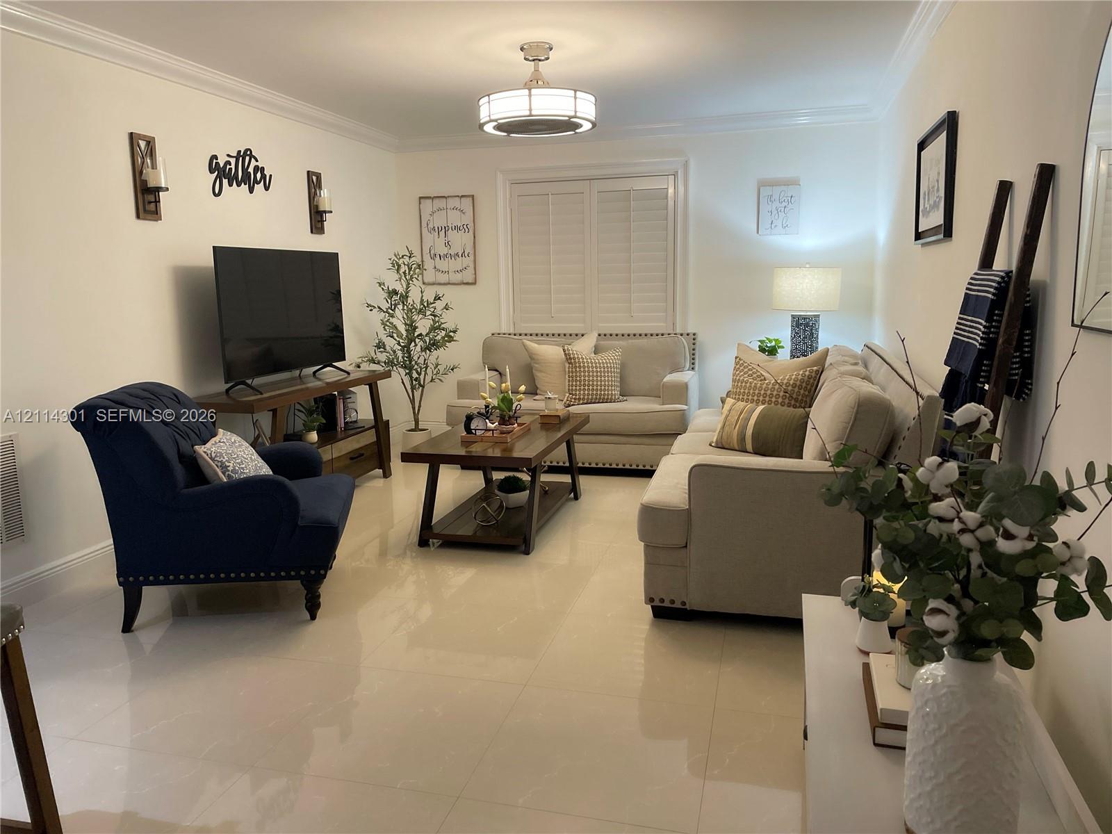 Polished tile flooring, crown molding, plantation shutters, and a central drum-style ceiling light fixture
