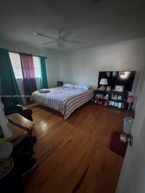 Room featuring wood-finish flooring, a multi-blade ceiling fan, and horizontal blinds Room featuring wood-finish flooring, a multi-blade ceiling fan, and horizontal blinds