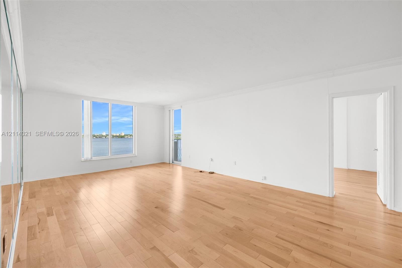 Open-concept room featuring wood-finish flooring, large windows, mirrored wall panels, and water scenery