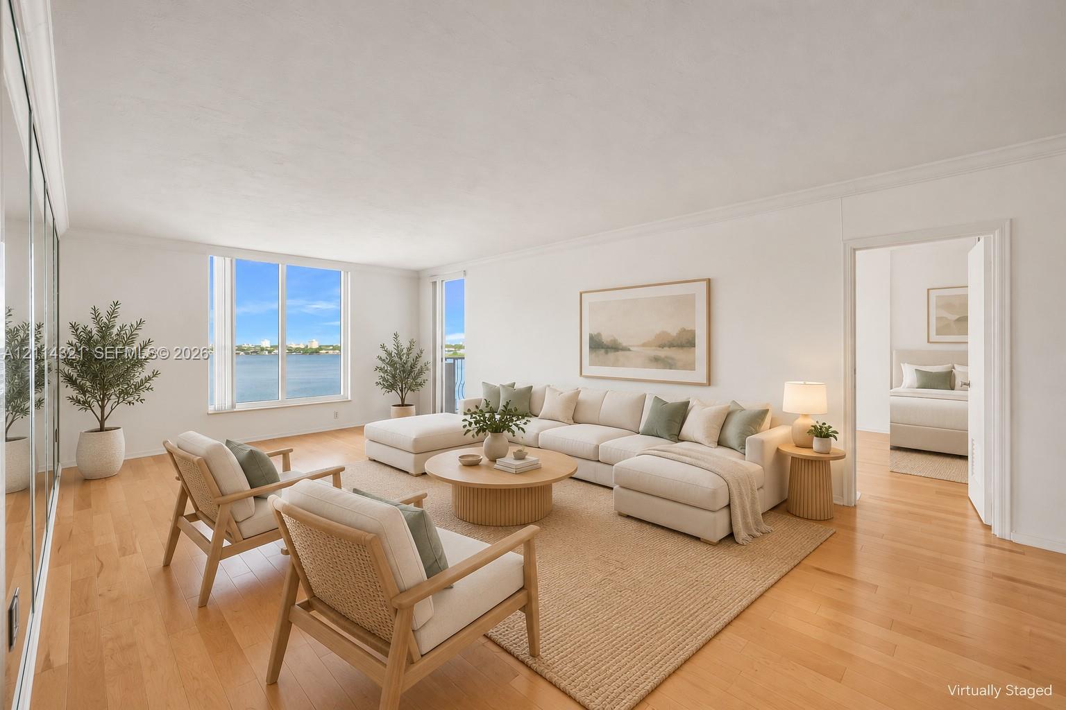 Living area featuring wood-finish flooring, floor-to-ceiling mirrored wall paneling, and expansive windows with water scenery