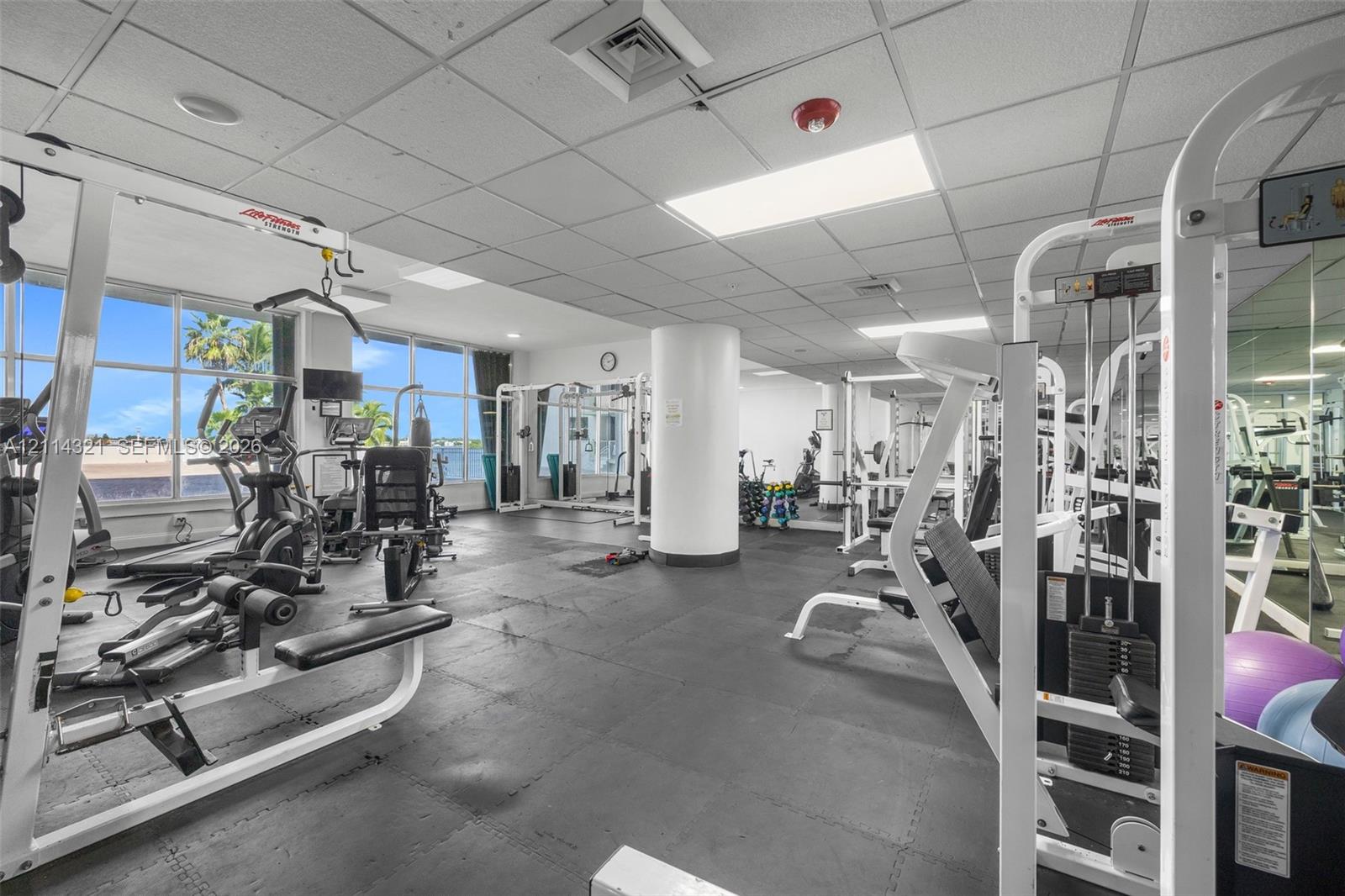 Fitness center featuring rubber flooring, floor-to-ceiling windows, and wall-to-wall mirrors