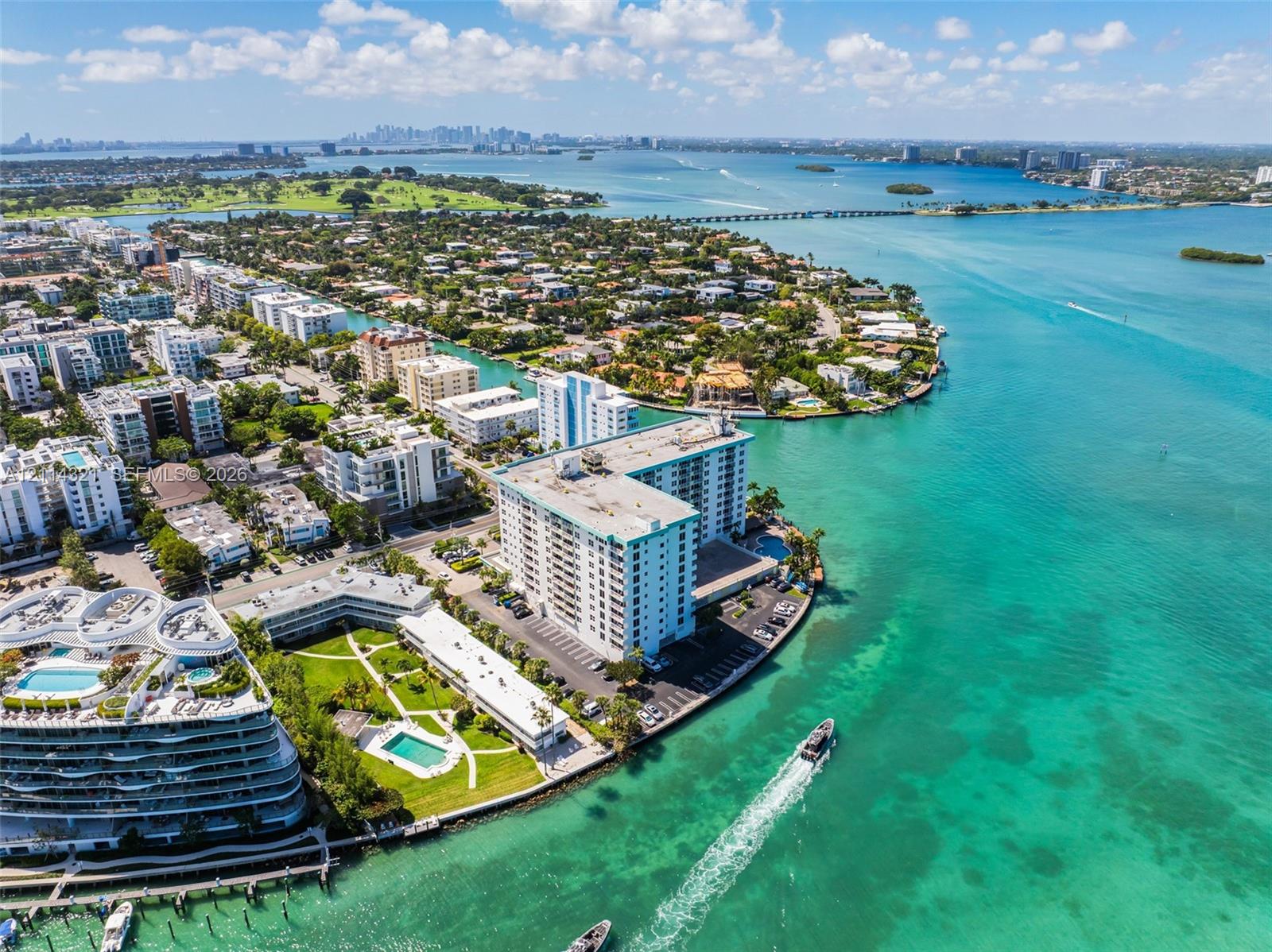Aerial perspective of a high-rise waterfront condominium complex featuring direct shoreline access and surrounding tropical landscape