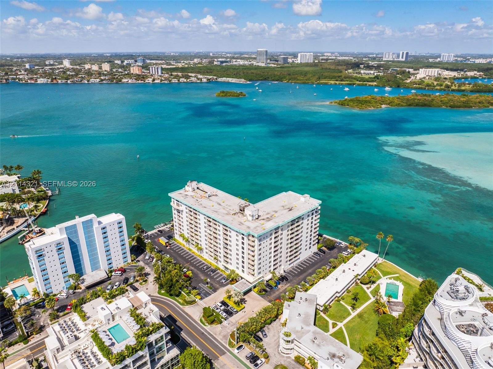 Waterfront high-rise building situated on a peninsula, featuring on-site paved parking, manicured landscaping, and immediate proximity to the open bay