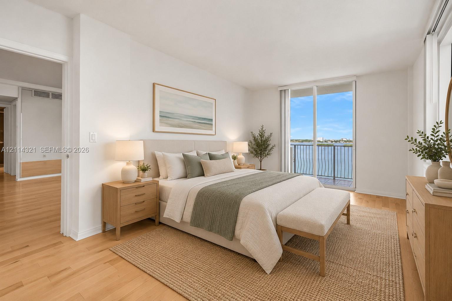 Neutral-toned room featuring wood-finish flooring, floor-to-ceiling glass sliding doors, and a private balcony with metal railing