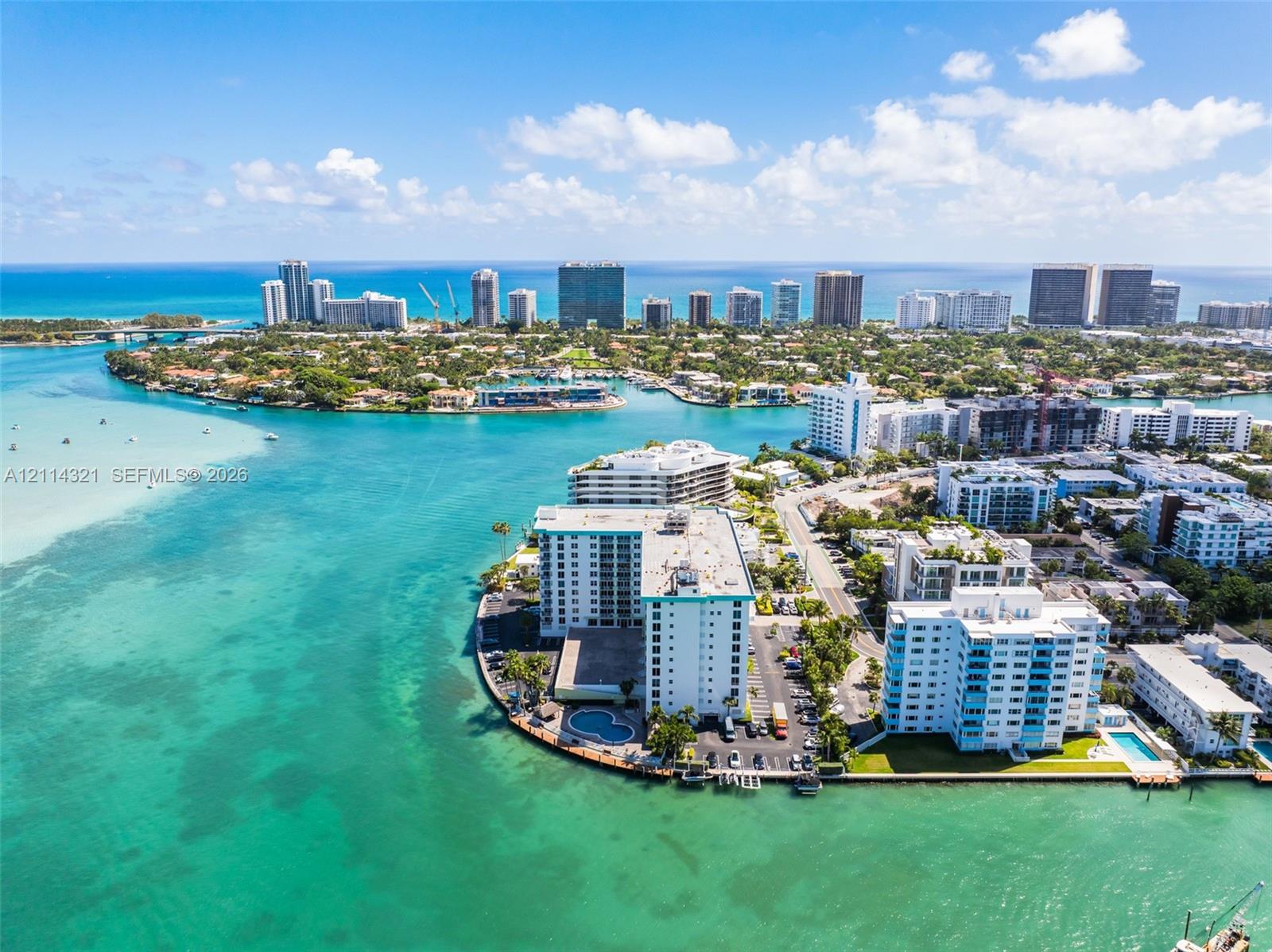 Aerial perspective featuring a waterfront high-rise building with a private swimming pool, situated on a coastal peninsula with direct water access