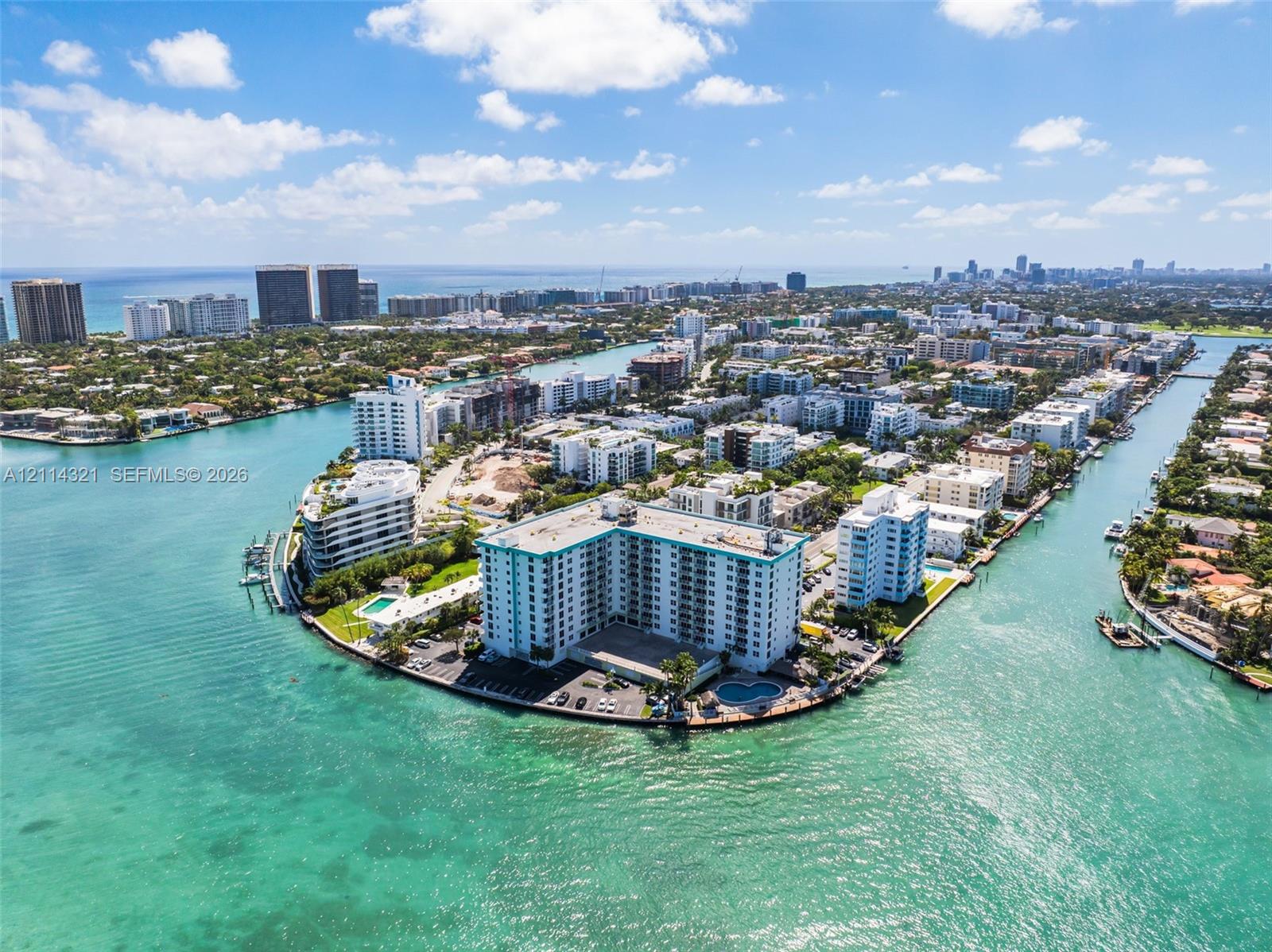 Waterfront high-rise building situated on a peninsula, featuring exterior surface parking, a ground-level pool, and direct access to surrounding waterways