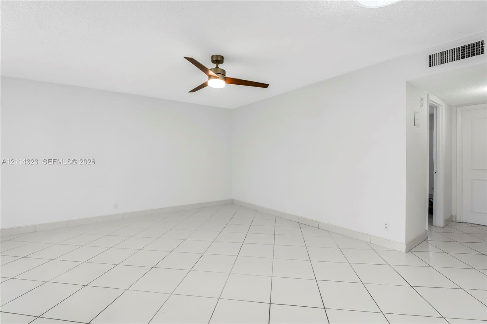 Interior space featuring ceramic tile flooring, neutral wall finishes, and a central ceiling fan with an integrated light fixture
