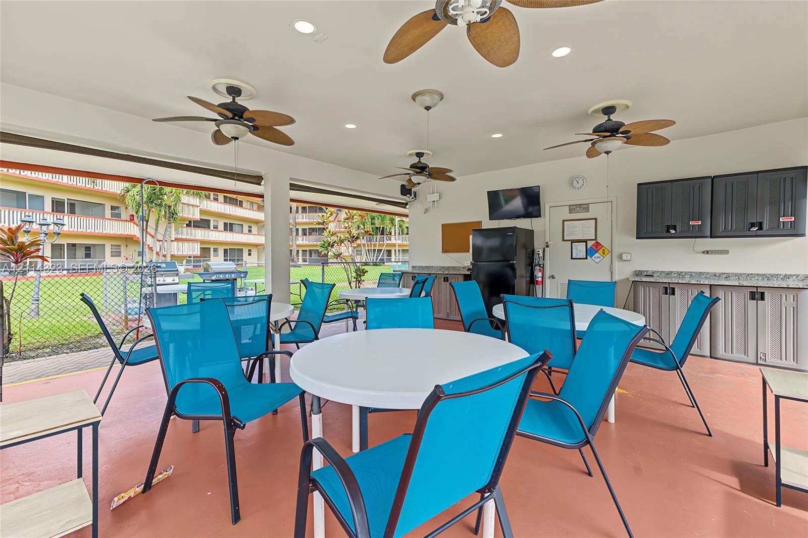 Covered outdoor pavilion featuring built-in cabinetry, recessed lighting, ceiling fans, and stone-finish countertops