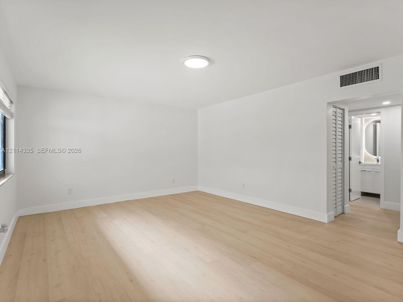Room featuring wood-finish flooring, a neutral color palette, recessed lighting, and a louvered closet door