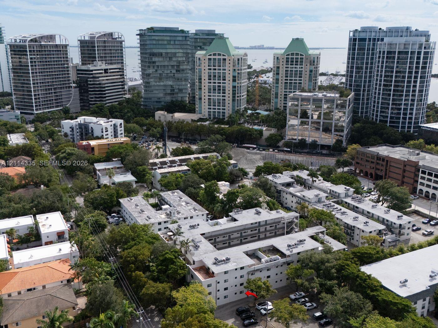 Aerial perspective featuring multi-story residential structures, mature tree canopy, and proximity to the waterfront