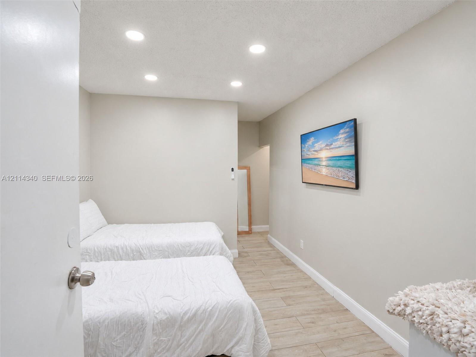 Interior room featuring wood-finish tile flooring, neutral wall paint, and recessed ceiling lighting