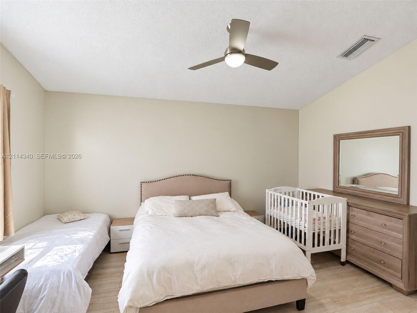 Vaulted ceilings, neutral wall tones, wood-finish flooring, and a modern brushed-nickel ceiling fan with integrated lighting