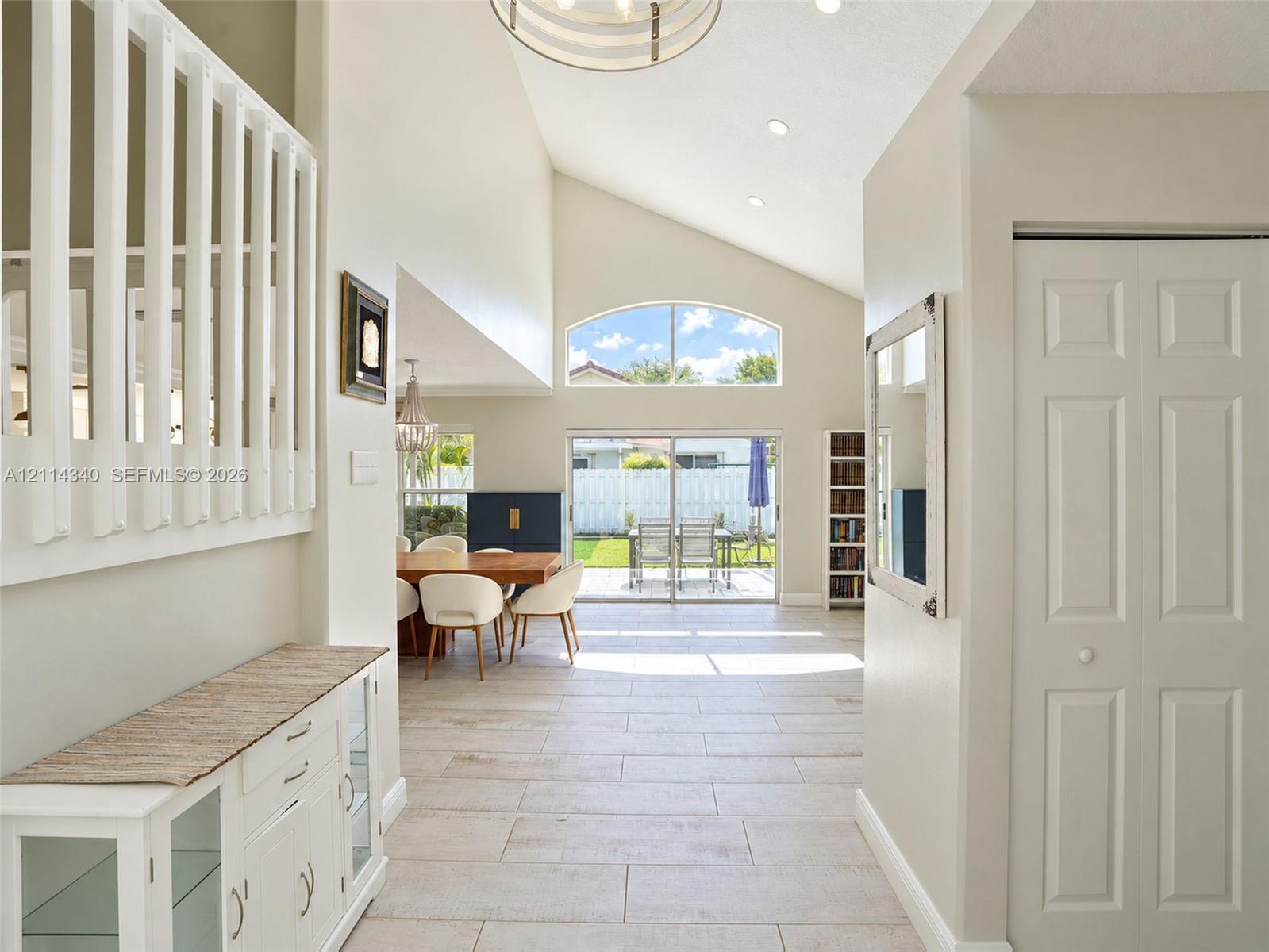 Vaulted ceilings, arched window, tile flooring, recessed lighting, and sliding glass doors