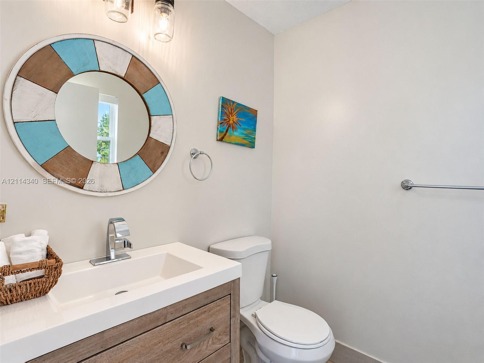 Wood-finish vanity cabinet with a white countertop and integrated sink, polished chrome faucet, and dual wall-mounted pendant light fixtures