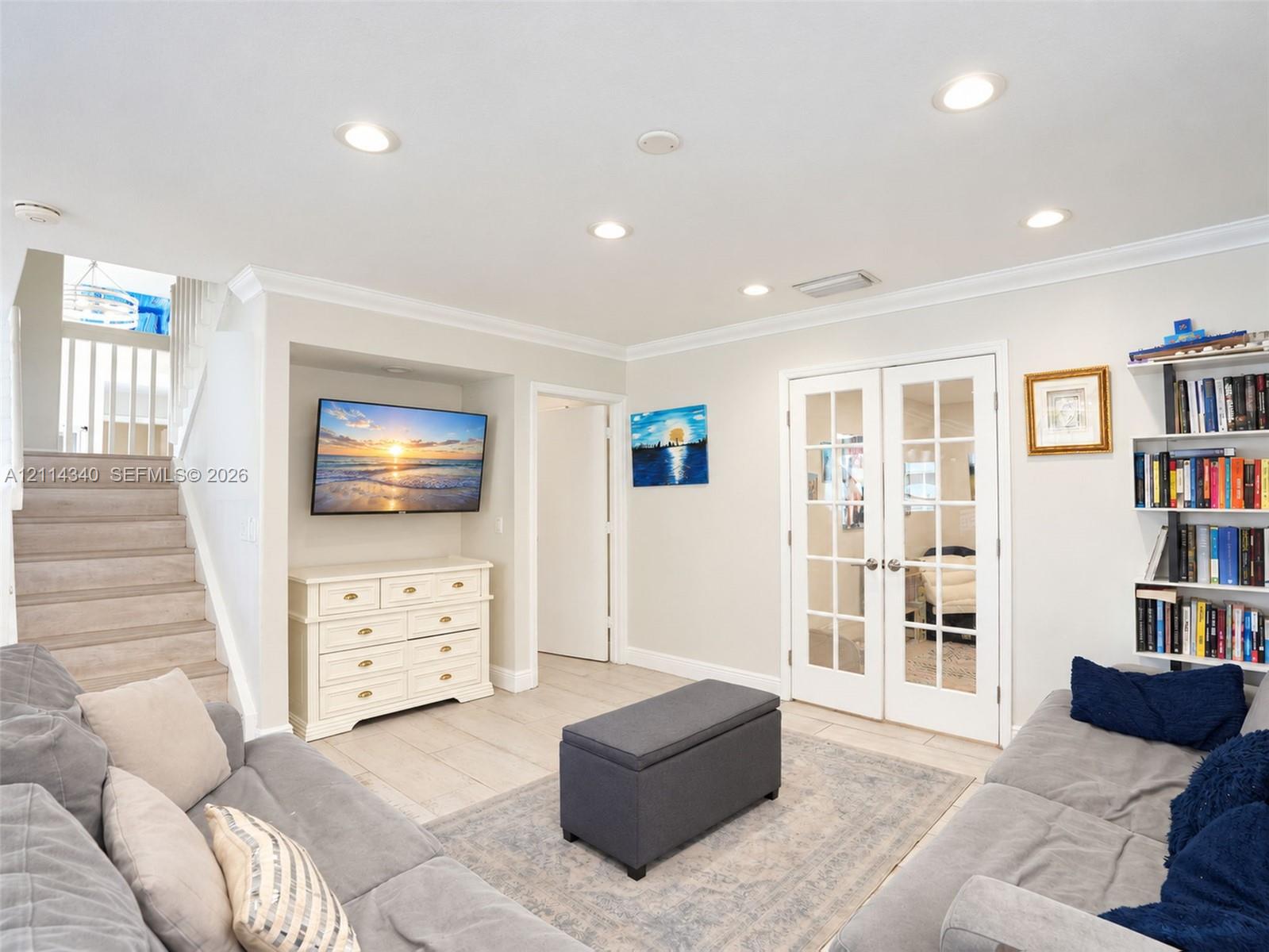 Living area featuring recessed lighting, crown molding, tile flooring, built-in shelving, and double French doors with glass panes