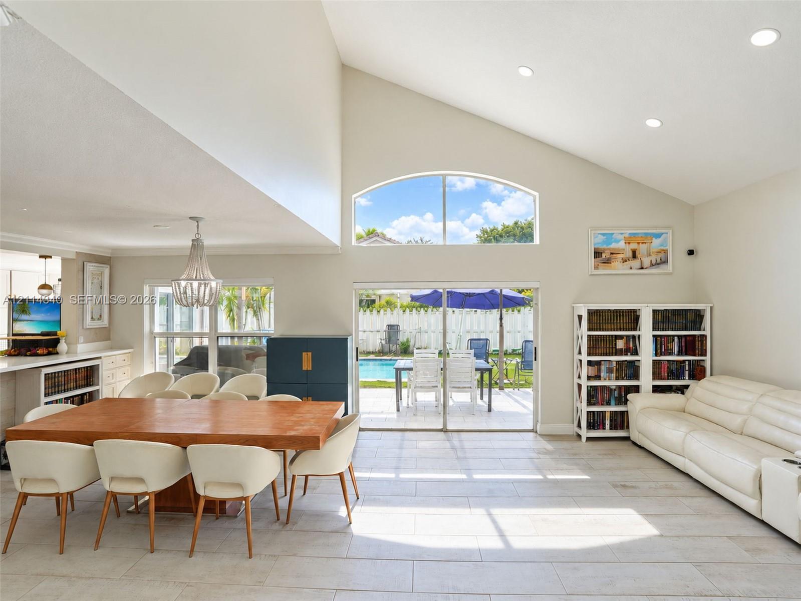 Vaulted ceilings, arched transom window, recessed lighting, tile flooring, and glass sliding doors