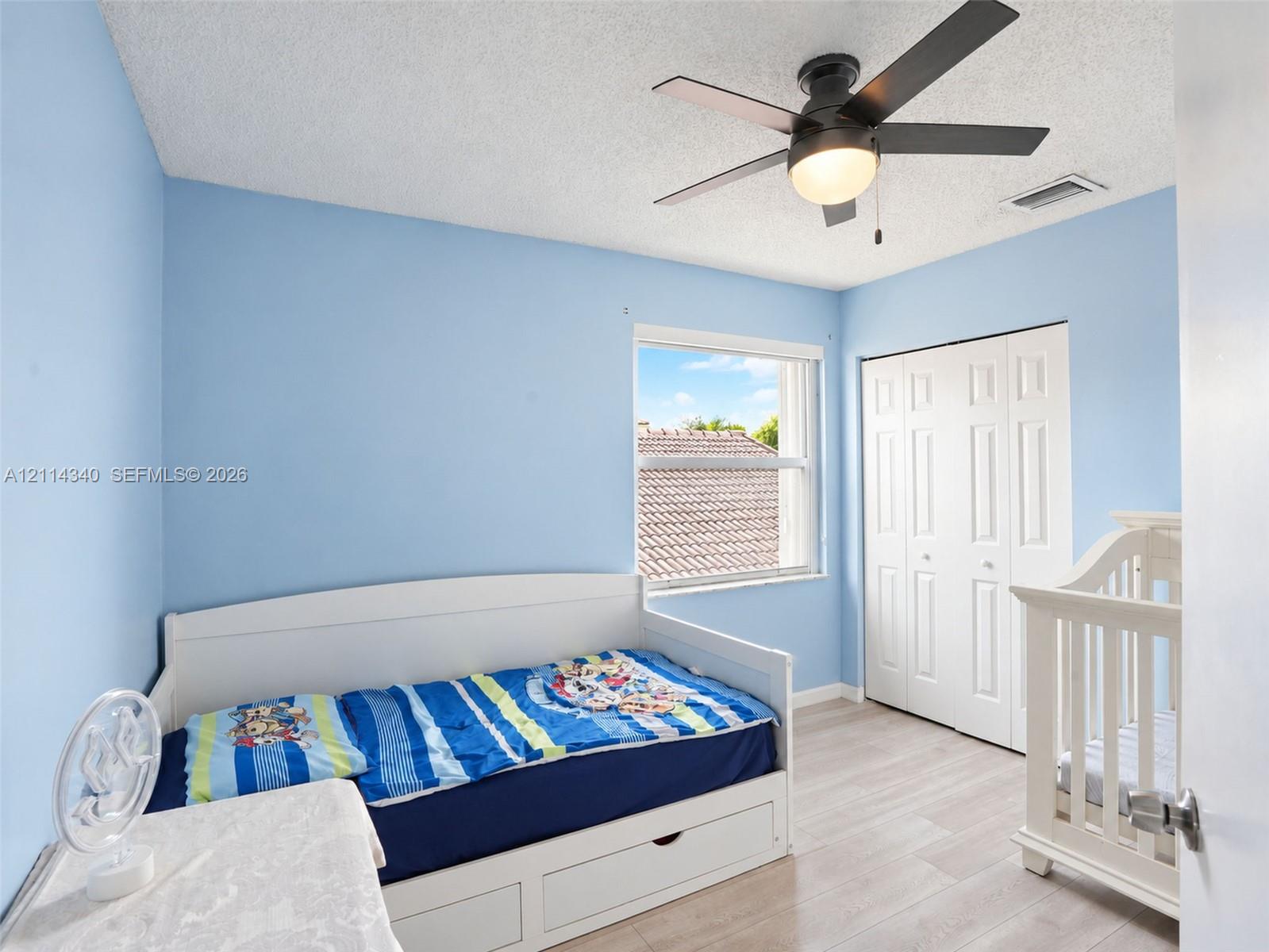 Room featuring wood-finish flooring, a multi-panel bi-fold closet, a ceiling fan with integrated light fixture, and a single-hung window