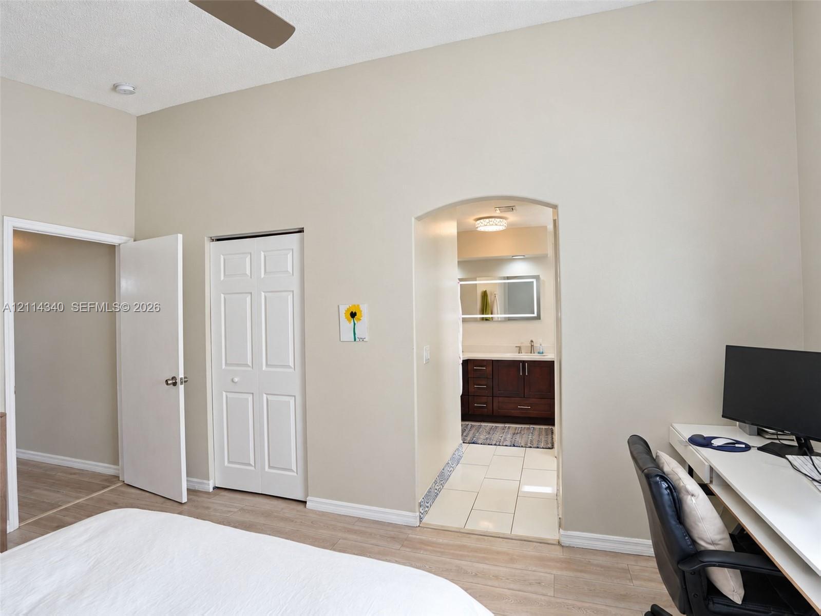 High ceilings, arched doorway, wood-finish flooring, and white interior doors