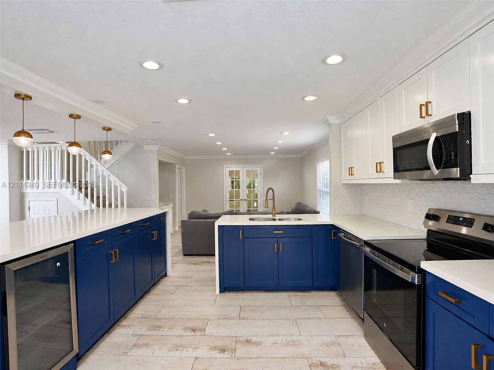 Kitchen featuring custom blue and white cabinetry, quartz countertops, scalloped tile backsplash, recessed lighting, and wood-finish tile flooring