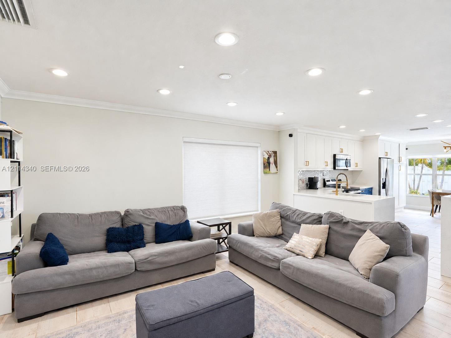 Open-concept interior featuring recessed lighting, crown molding, neutral wall finishes, tile flooring, and white cabinetry