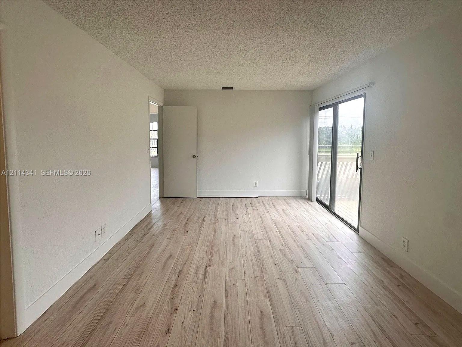 Interior space featuring wood-finish flooring, sliding glass door, and neutral wall tones Interior space featuring wood-finish flooring, sliding glass door, and neutral wall tones