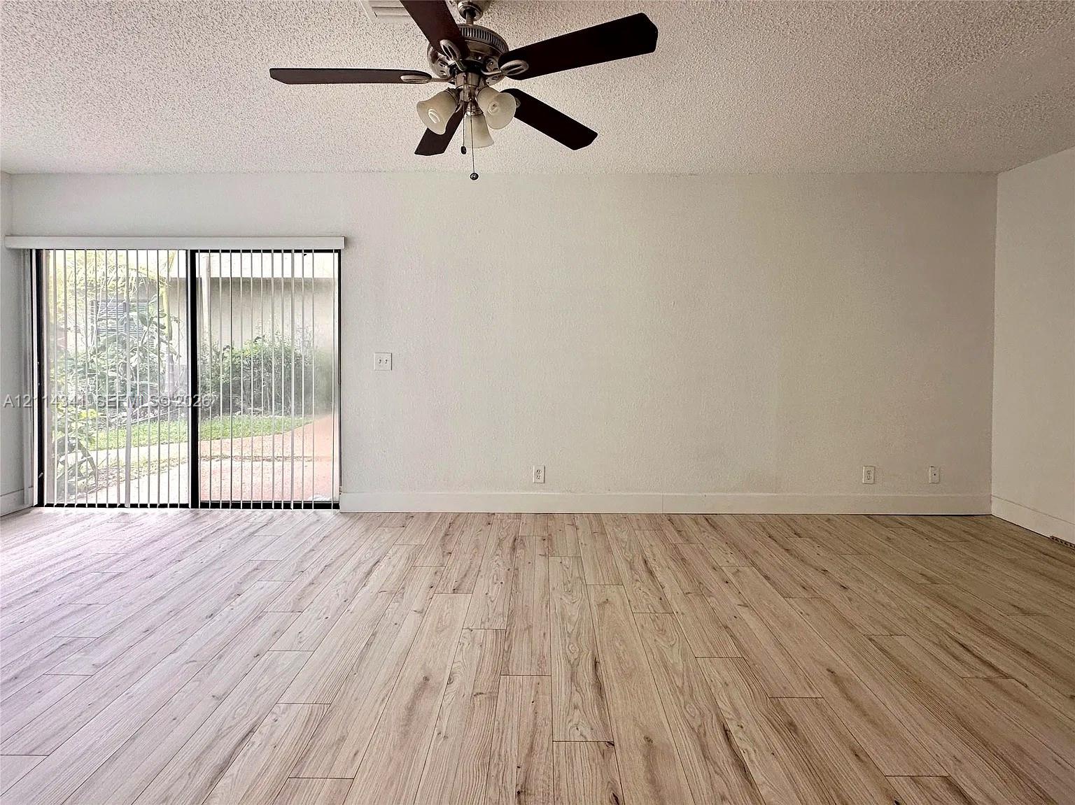 Interior space featuring wood-finish flooring, sliding glass patio doors, and a ceiling-mounted fan with integrated lighting Interior space featuring wood-finish flooring, sliding glass patio doors, and a ceiling-mounted fan with integrated lighting