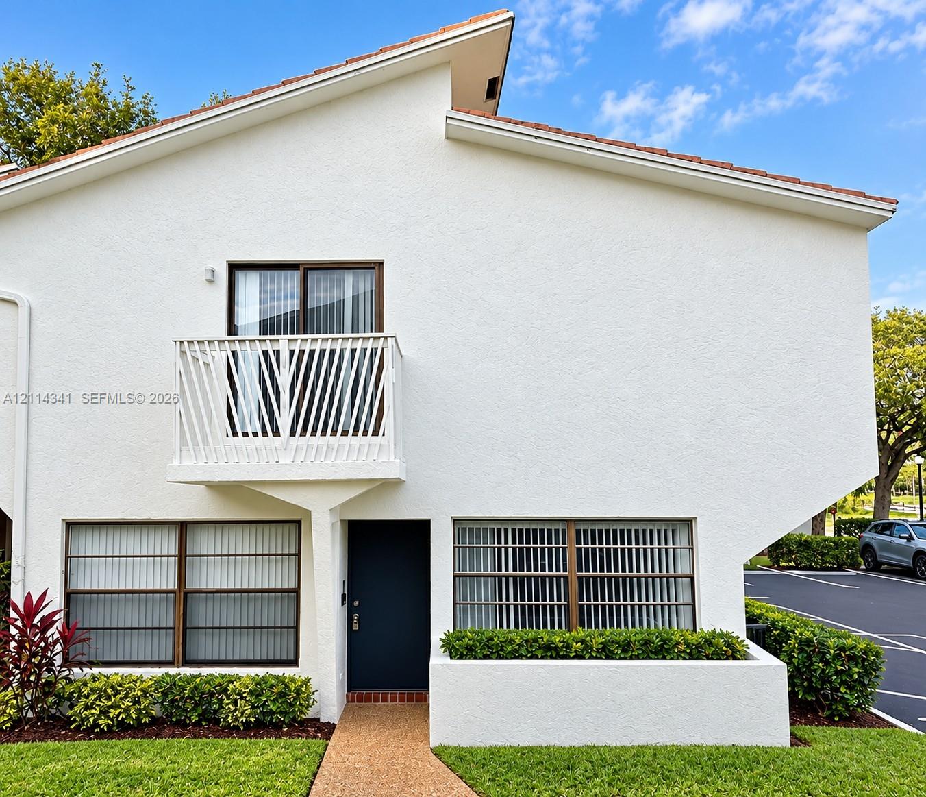 Stucco exterior featuring an asymmetric roofline, a second-story balcony with metal railing, and a built-in planter box Stucco exterior featuring an asymmetric roofline, a second-story balcony with metal railing, and a built-in planter box