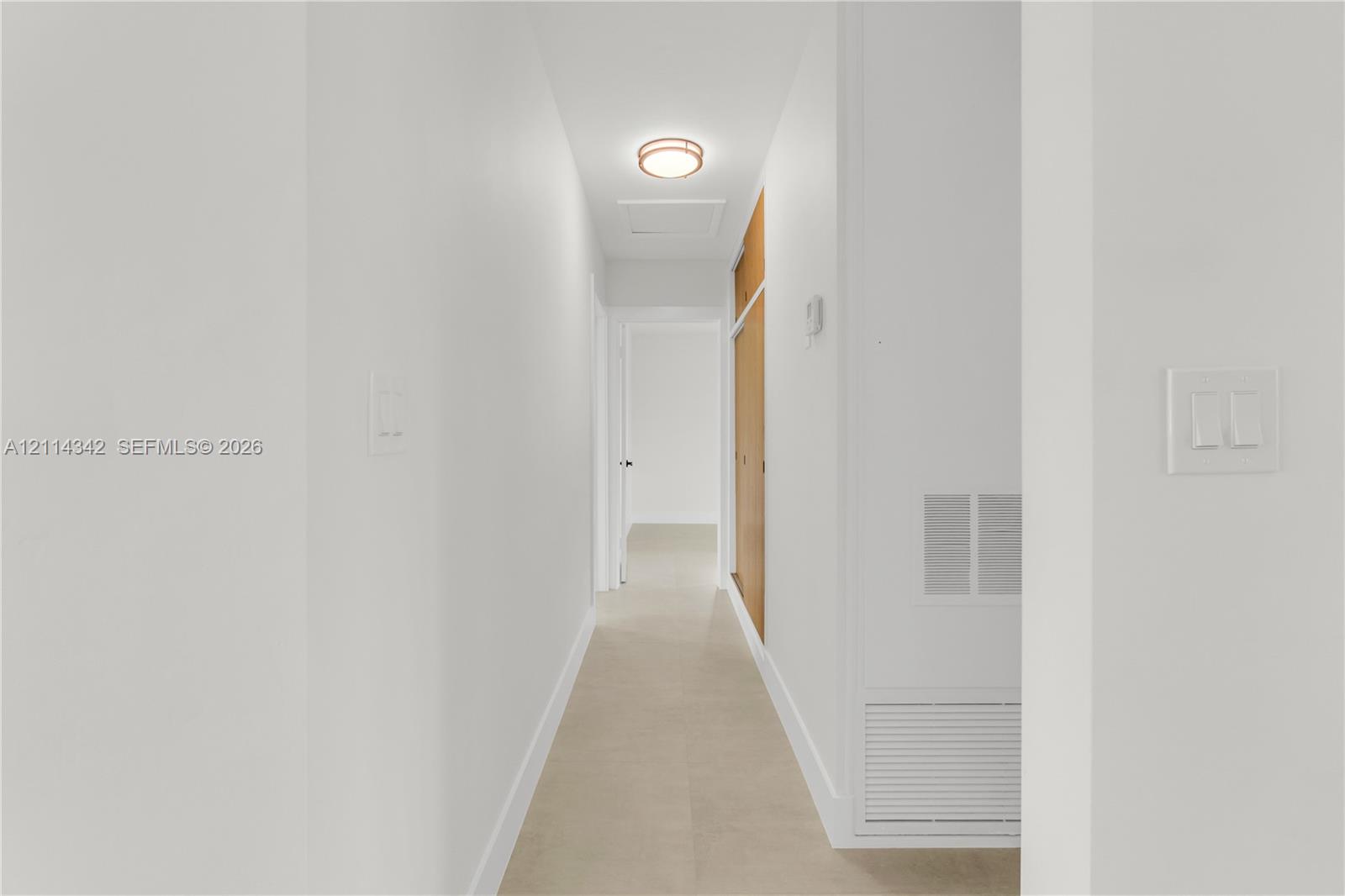 Neutral color palette, tile flooring, flush-mount circular lighting fixture, and floor-to-ceiling wooden cabinetry