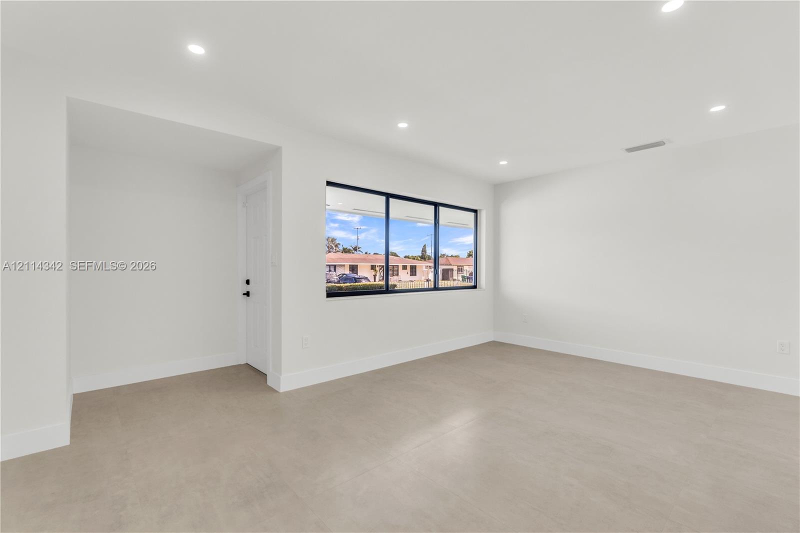 Neutral interior featuring expansive windows with black frames, recessed lighting, and large-format tile flooring