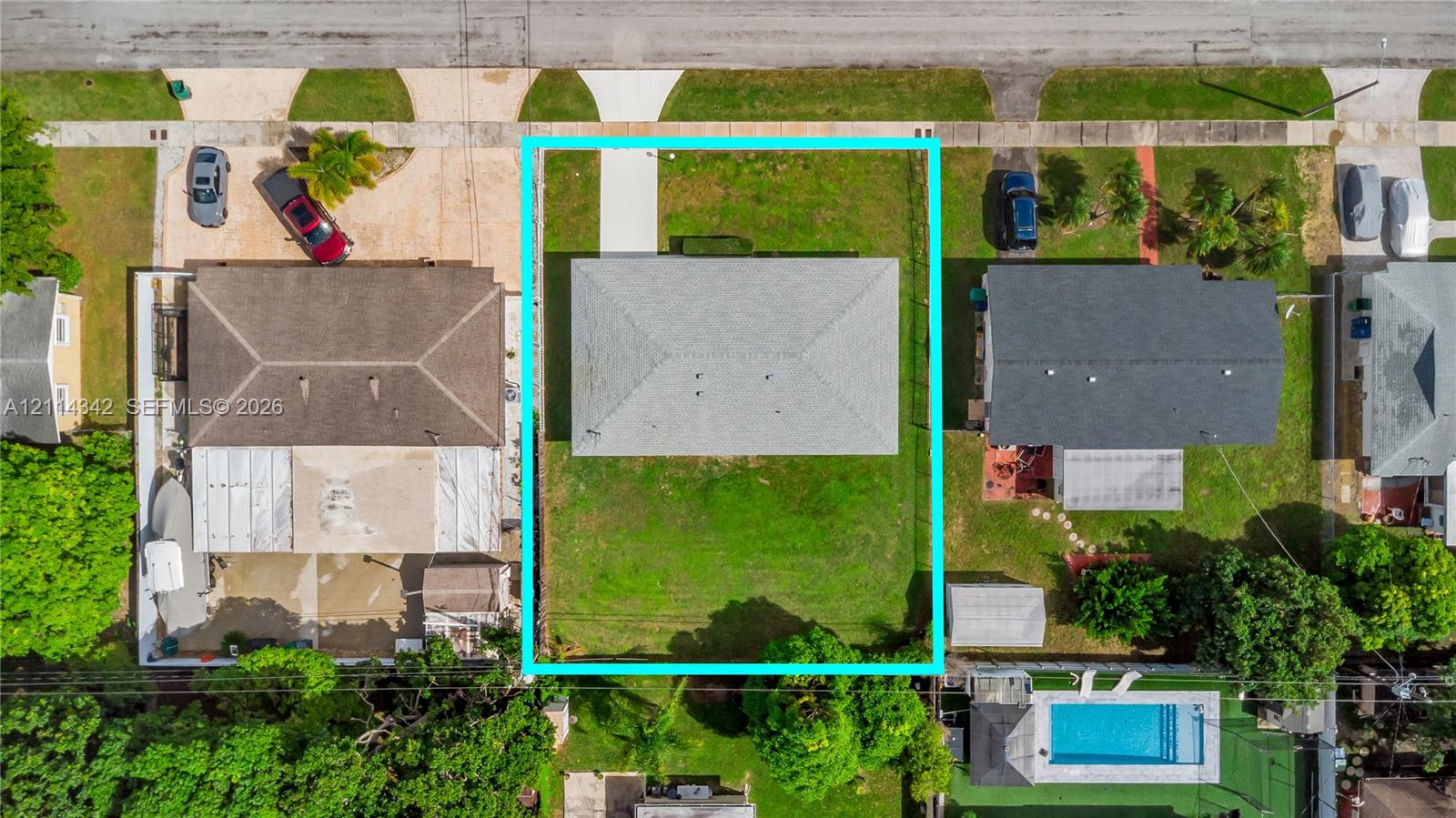 Aerial perspective of a rectangular lot featuring a hip-style roof, a paved concrete driveway, and expansive lawn space
