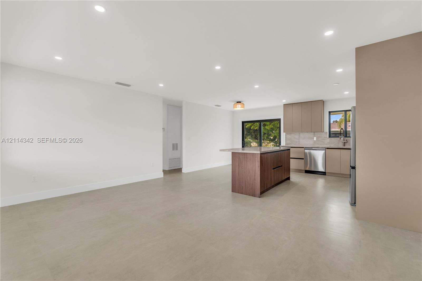 Open-concept kitchen featuring a center island, recessed lighting, stainless steel appliances, flat-panel cabinetry, and large-format tile flooring