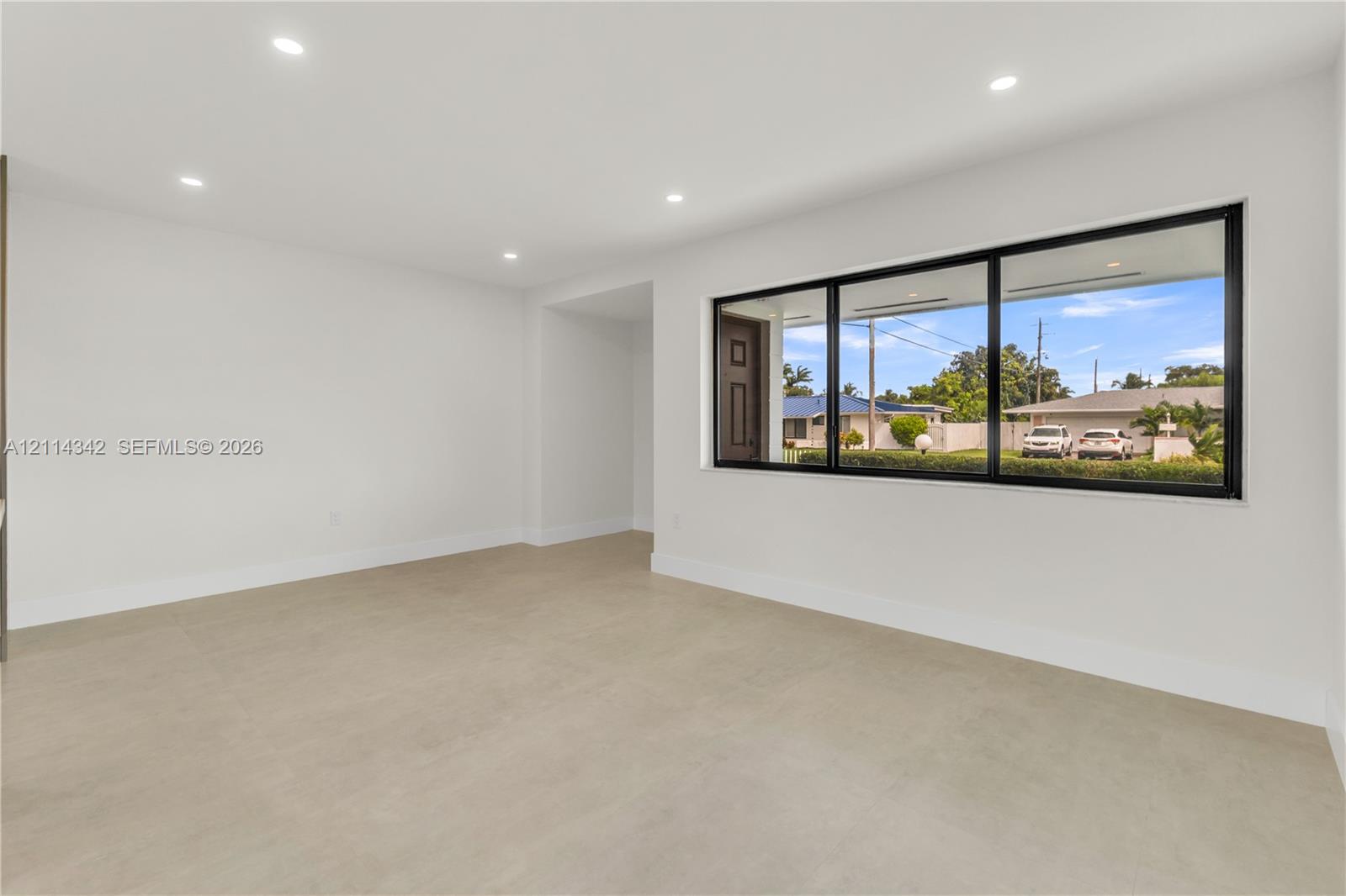 Interior space featuring neutral large-format tile flooring, recessed ceiling lighting, and a wide window with a black frame