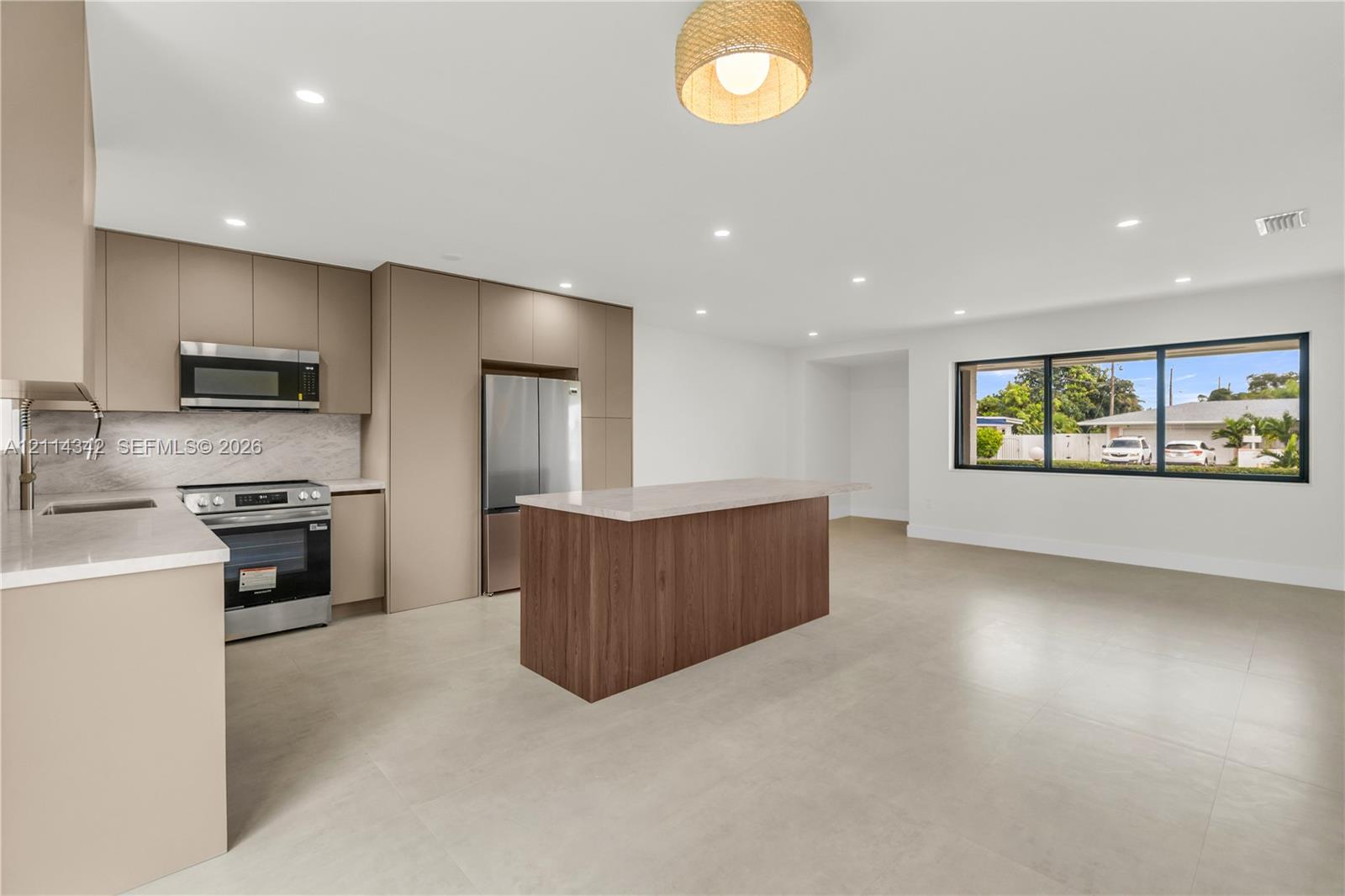 Kitchen featuring flat-panel cabinetry, a wood-finish island, solid-surface countertops, stainless steel appliances, and tile flooring
