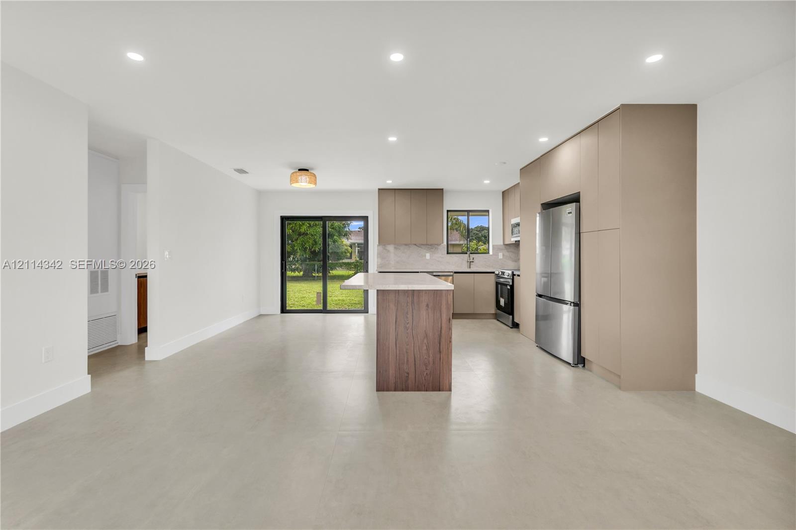Kitchen featuring a central island, flat-panel cabinetry, stainless steel refrigerator, recessed lighting, and sliding glass doors
