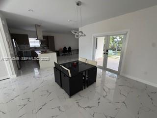 Polished stone-finish tile flooring, kitchen island with built-in cabinetry, stainless steel range hood, recessed lighting, and double glass pane doors Polished stone-finish tile flooring, kitchen island with built-in cabinetry, stainless steel range hood, recessed lighting, and double glass pane doors