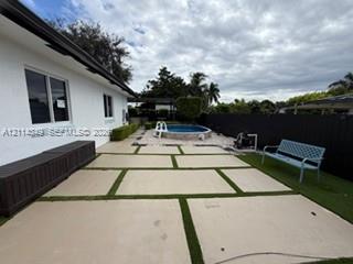 Outdoor patio featuring large-format concrete pavers with turf inlay, above-ground pool with stone-finish surround, and perimeter privacy fencing