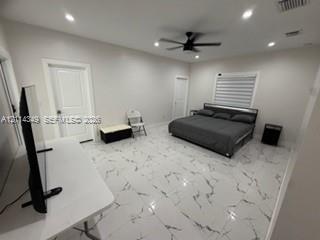 Spacious room featuring light-toned large-format tile flooring with veining, recessed lighting, a modern ceiling fan, and paneled doors