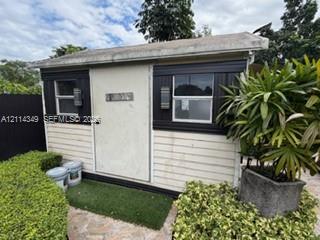 Detached structure featuring horizontal siding, dual windows with black trim, and wall-mounted exterior lighting