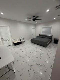 Large-format tile flooring with a veined pattern, recessed ceiling lighting, and a central ceiling fan