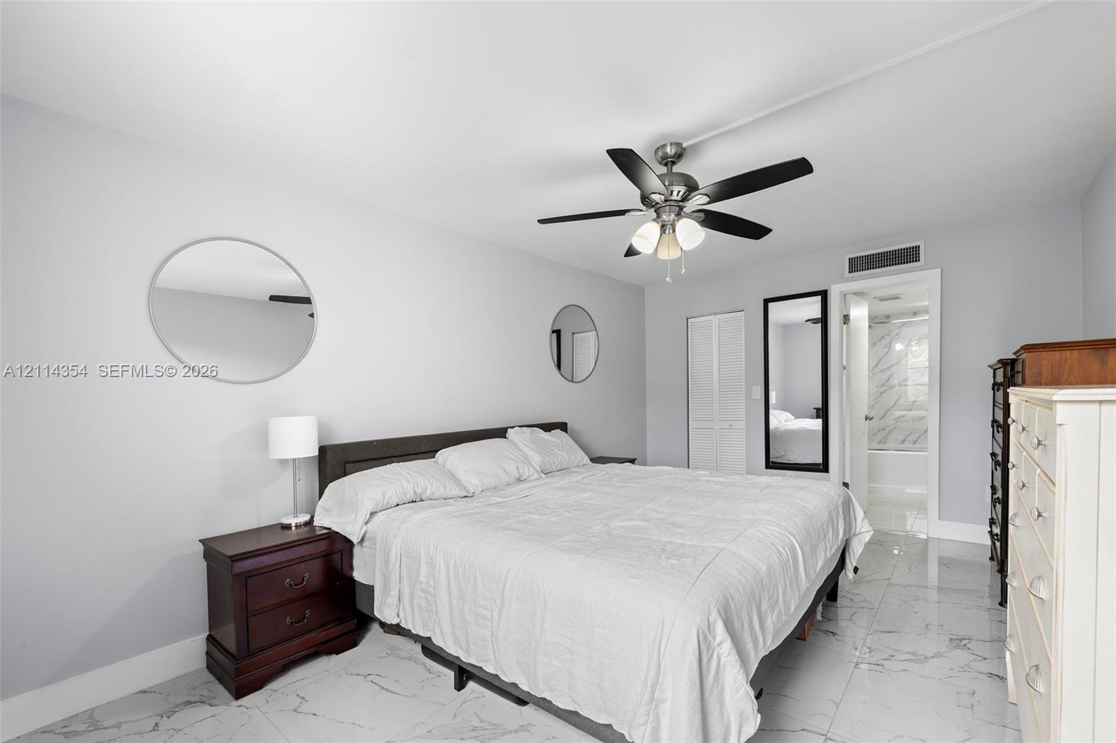 Neutral-toned interior featuring polished stone-finish flooring, a multi-blade ceiling fan with integrated lighting, and a closet with bifold doors