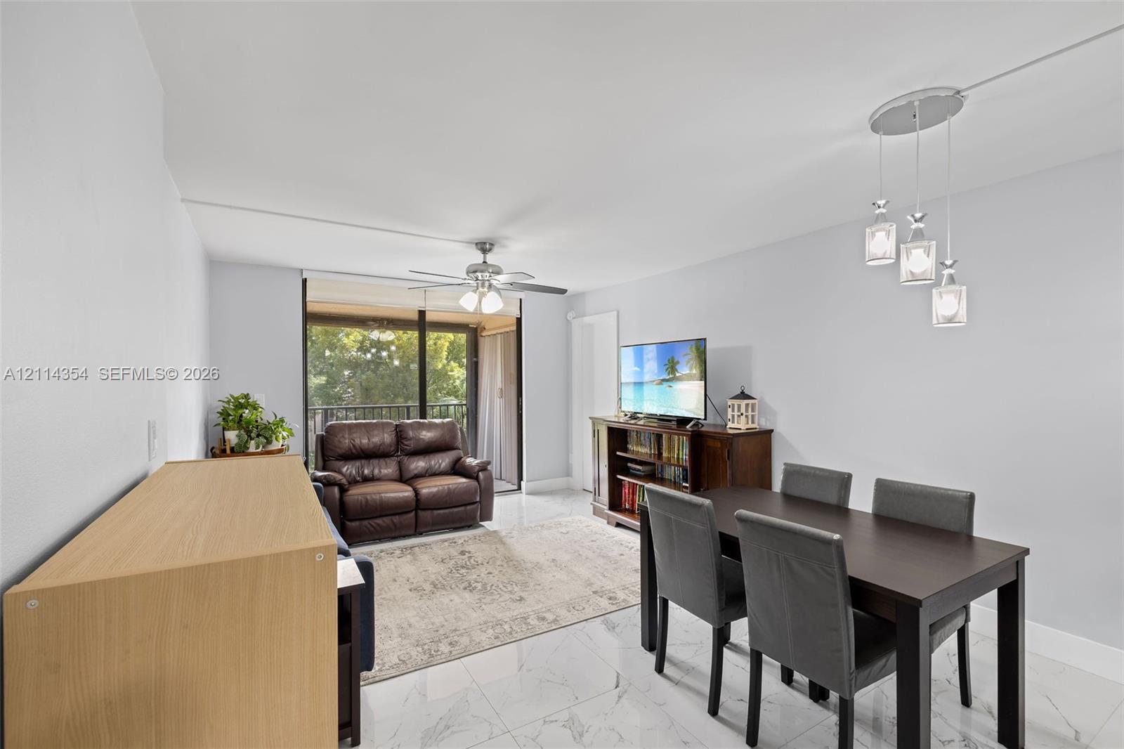 Open-concept living space featuring large-format tile flooring, a multi-light pendant fixture, and a ceiling fan with integrated lighting